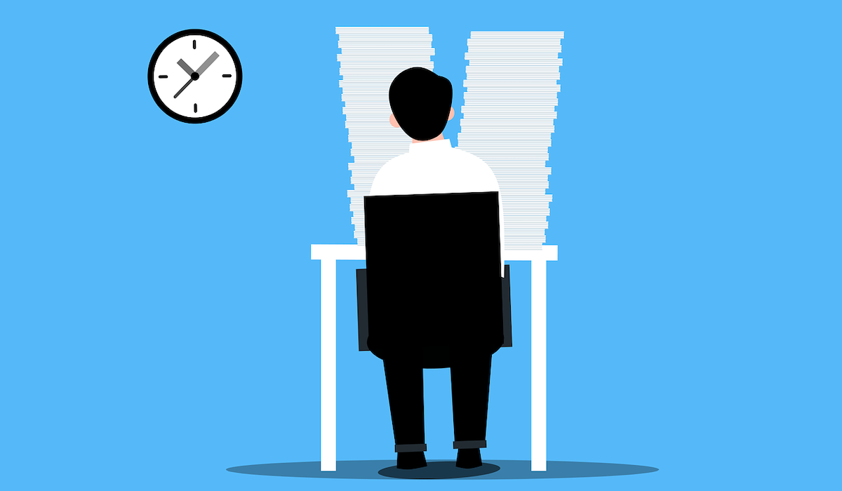 Graphic of man sitting at office desk with piles of paper before him 