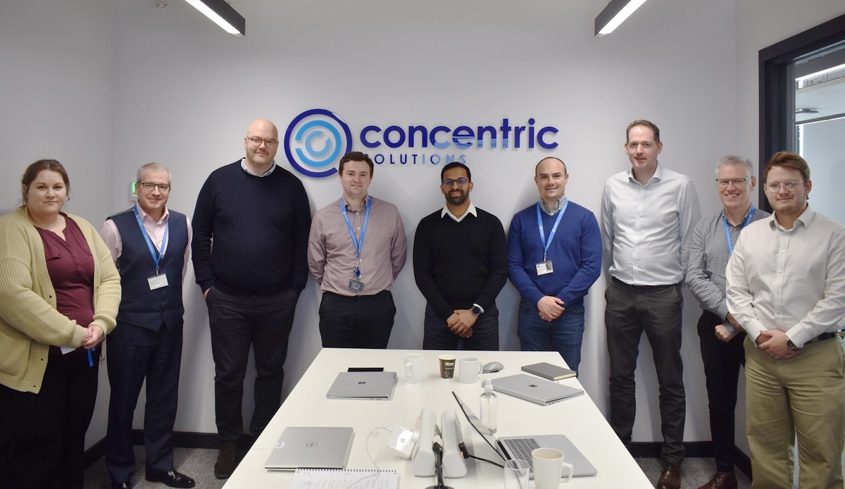 An image of the Concentric team standing in front of their corporate signage Concentric Team